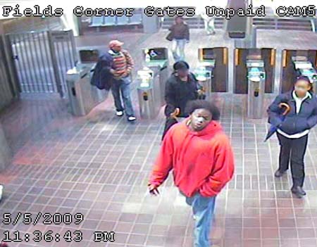 Person of interest: Boston Police think this man in red â€”shown at the Fields Corner T station on Tuesday â€” may be a suspect in a string of armed robberies. Police want to identify him and the woman holding an umbrella at right.