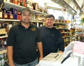 New owner, old owner: Jay Patel and Harry Gerogoulopolous split the watch behind Ashmont Market's main counter on Tuesday. Photo by Bill Forry