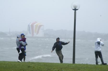 Tropical storm watchers: A group of people tested their balance against Tropical Storm Irene's strong gusts this morning on the UMass-Boston campus along Dorchester Bay. Photo by Bill Forry