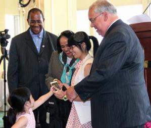 Valedictorian salute: A younger family member delivers a cell phone to Excel High School valedictorian Thao Nguyen as she received her award from Boston School Committee Chair Rev. Dr. Gregory G. Groover, Supt. Carol R. Johnson and Mayor Tom Menino. Photo by Elizabeth Murray