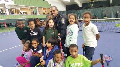 Deputy Superintendent Joseph Harris is shown with children who participate in the Volley Against Violence program at Sportsmen’s Tennis Club in Dorchester.