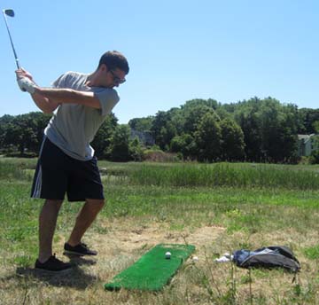 FORE!: During a week that offered a perfect stretch of summer weather for outdoor activities, Luke Baroski, above, and his friend Conor Farrell took turns Tuesday afternoon hitting golf shots from a makeshift driving range at Patten’s Cove in Savin Hill. Photo b