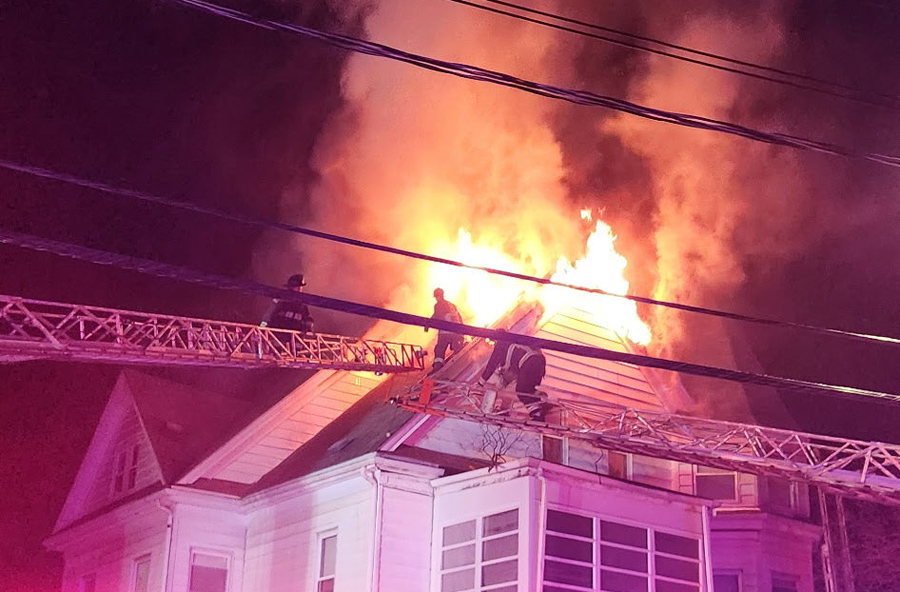 Firefighters as flames burst through roof, photo by Boston Fire Department